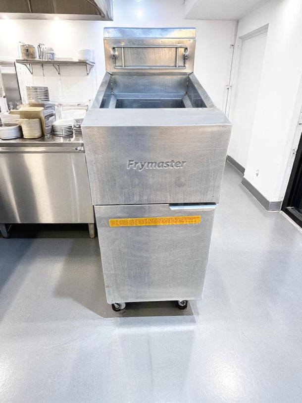 Frymaster commercial fryer, stainless steel, on casters. Visible brand logo, control panel, and safety label. Good condition.
