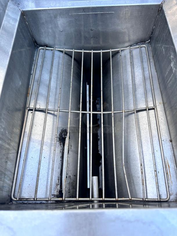 Commercial deep fryer basket, stainless steel with wire rack, showing signs of wear and residue, ideal for heavy-duty use.