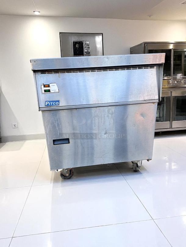 Pitco commercial deep fryer with stainless steel exterior, on wheels for mobility. Visible wear and stains, electrical controls intact.