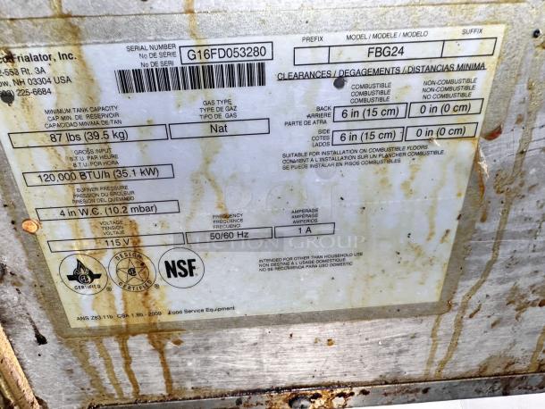 Metal label displaying serial number G16FD053280, model FBG24. Indicates 120,000 BTU/h, natural gas, 115V, NSF certified. Worn condition.