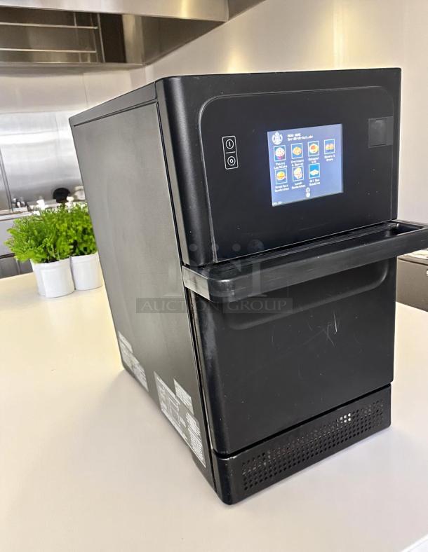 Black countertop commercial oven with touchscreen interface. Features various cooking programs. Appears in good condition.