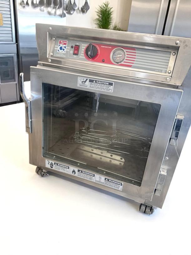 Stainless steel Metro C5 warming cabinet with temperature control, glass door, and safety labels. Good condition.