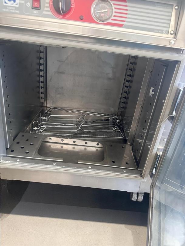 Commercial stainless steel warming cabinet, open door, temperature control dial, glass front, good condition.