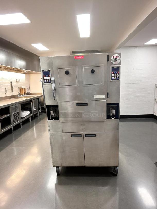 Commercial stainless steel fryer with double doors and keypad controls on front, mounted on wheels, in kitchen setting.
