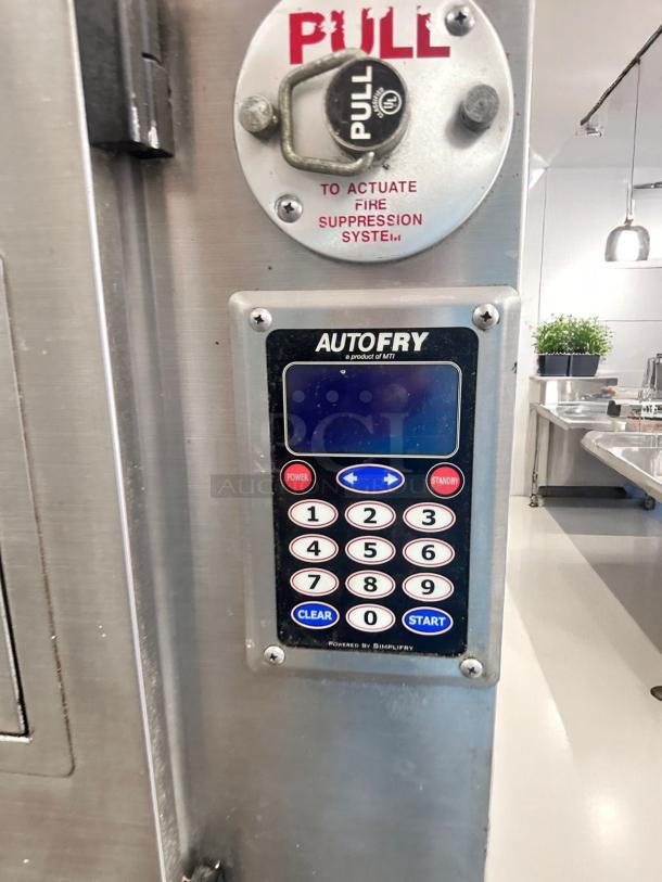 Autofry control panel with keypad and fire suppression activation lever. Stainless steel surface, commercial kitchen setting.