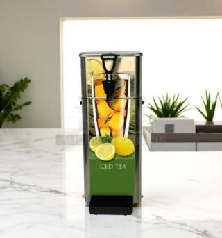 Tall stainless steel iced tea dispenser with lemon graphic, featuring a plastic tap and drip tray, set on a marble counter.
