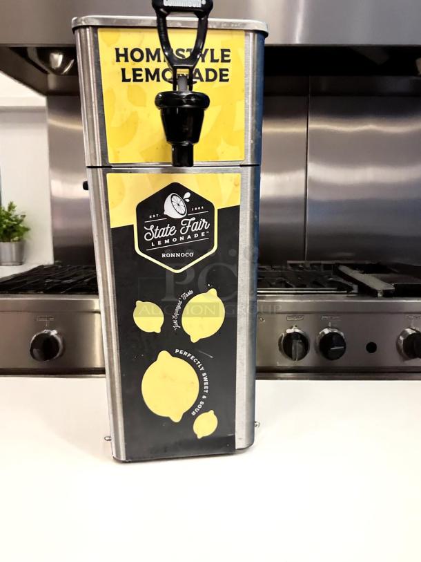 Stainless steel lemonade dispenser, "State Fair Lemonade", black and yellow lemon motif, good condition, Ronoco brand.
