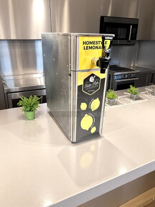 Commercial lemonade dispenser labeled "Homestyle Lemonade" and "State Fair Lemonade," stainless steel, countertop model.