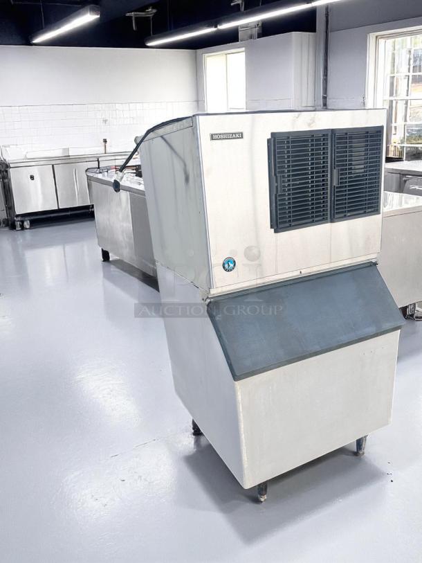 Hoshizaki ice maker in stainless steel, large capacity, industrial design, minor wear, situated in a clean commercial setting.