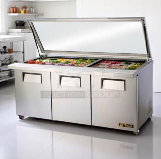Stainless steel commercial sandwich prep table with three-section refrigerator and open top, filled with fresh ingredients. Brand "True."
