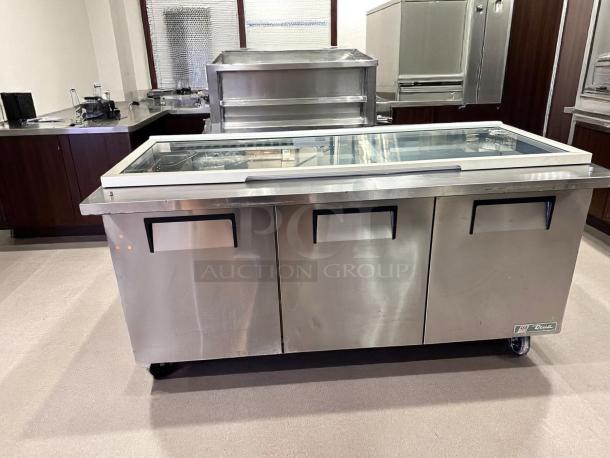 Stainless steel commercial refrigerated prep table by True, three-section, glass top, on wheels, in good condition.