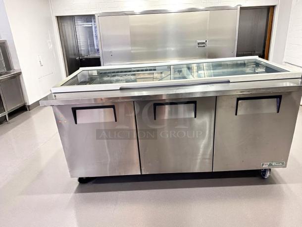 Stainless steel commercial refrigerator prep table with glass top, three compartments, True brand, on wheels, good condition.