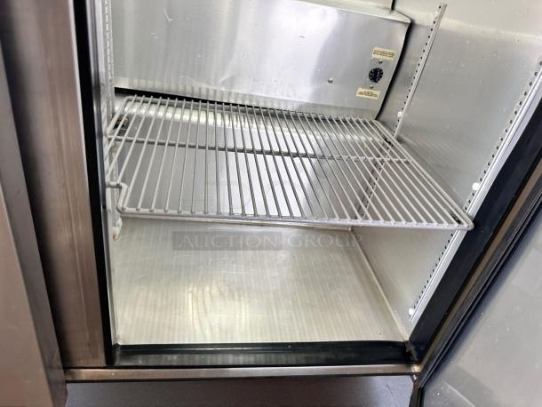 Commercial stainless steel refrigerator interior, featuring adjustable wire shelves and temperature control dial. Good condition.
