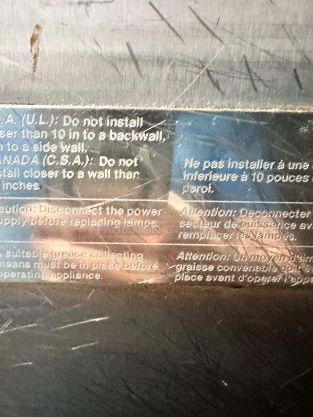 Metal appliance with scratched surface, featuring installation and safety instructions in English and French. Text includes wall installation guidelines and power disconnection warning.