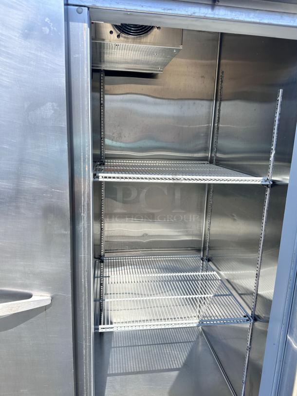 Commercial stainless steel refrigerator, interior view with shelves, in good condition, vent at top, suitable for industrial use.
