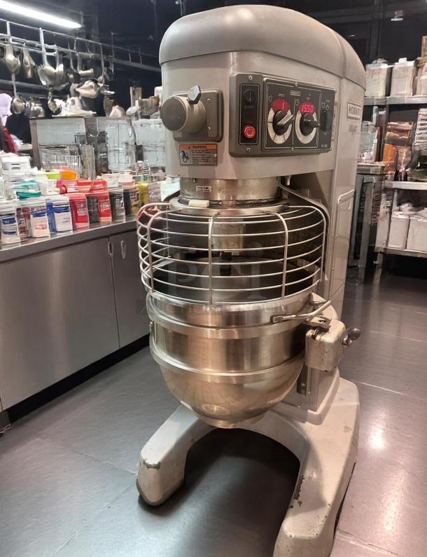 Hobart industrial mixer in good condition, stainless steel bowl, safety cage, and control panel with speed settings.