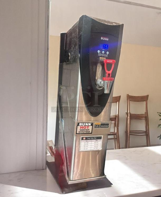 Bunn hot water dispenser with digital display, stainless steel body, and red tap, indicating "HOT WATER SYSTEM," in good condition.