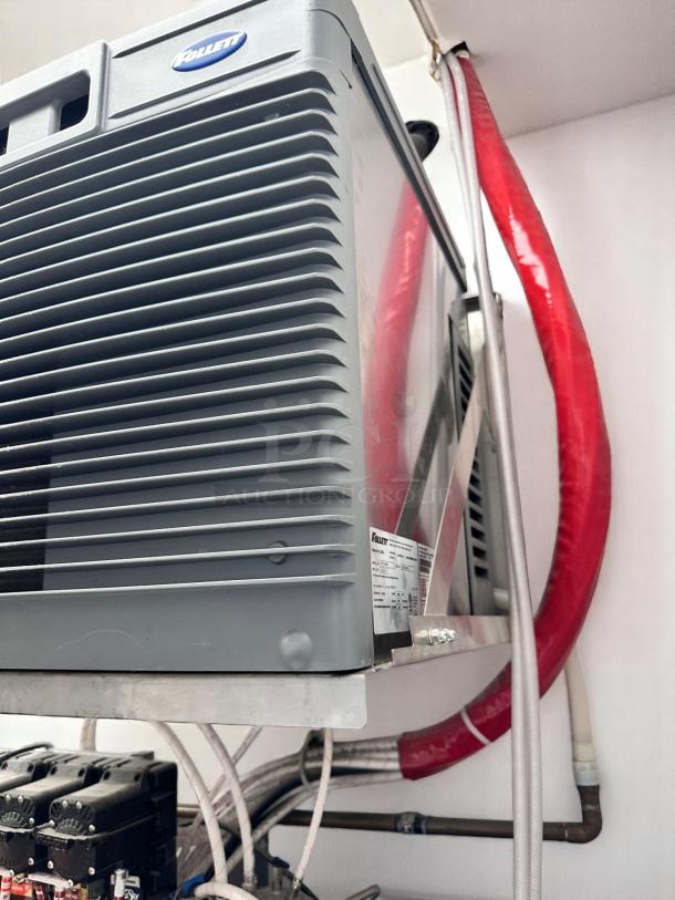 Follett ice machine with model label, in excellent condition, mounted in a storage area with visible red and white tubing.