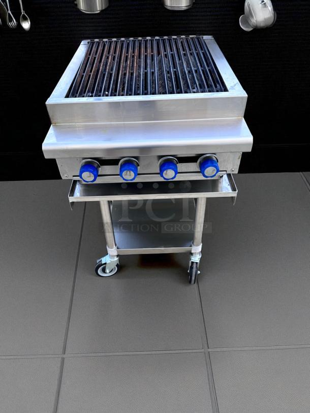 Stainless steel outdoor grill with four blue knobs, wheeled base, and storage shelf. Good condition with slight wear.