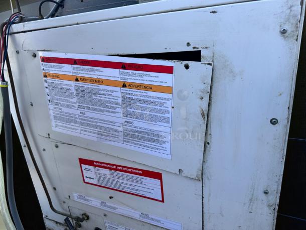 Industrial equipment panel with multiple warning labels in English, French, and Spanish. Panel shows signs of wear and dirt.
