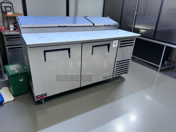 Commercial stainless steel refrigerated prep table with dual top lids, two-door cabinet, and caster wheels. Used condition.