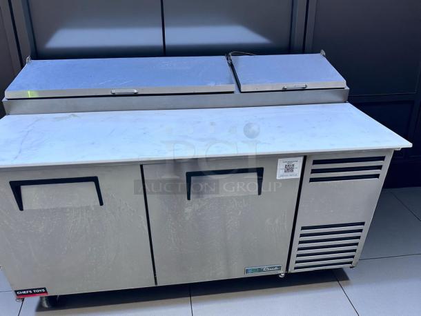 Stainless steel prep table with dual doors, refrigeration, and QR code label. Minor surface wear, Chef's Toys branding.