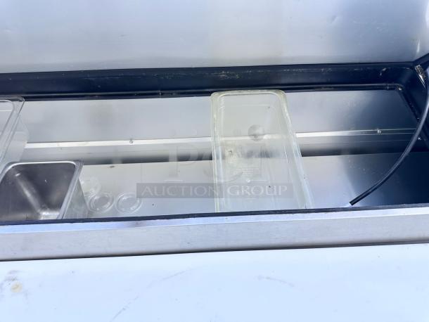 Commercial stainless steel refrigerated prep table with multiple compartments. Includes clear plastic food pans. Good condition.