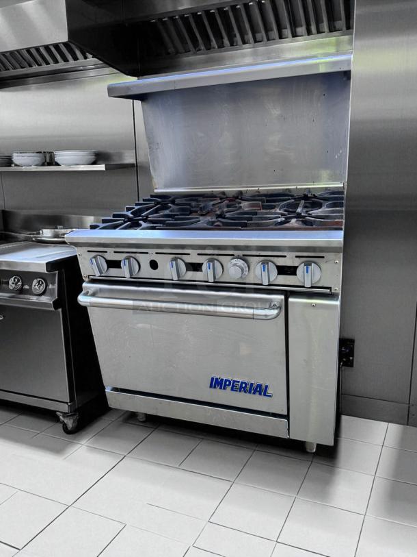 Commercial Imperial stove with six burners and oven, stainless steel, used condition, logo visible on oven door.