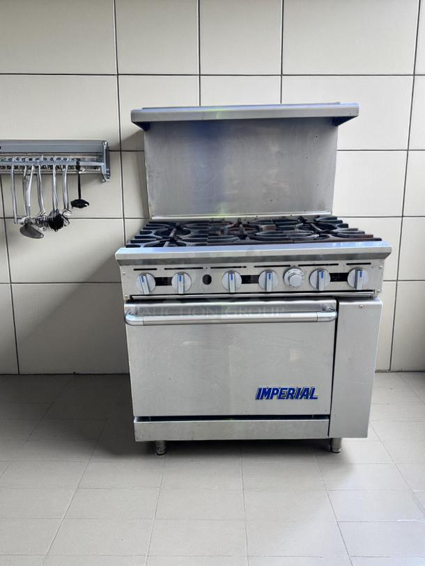 Stainless steel Imperial six-burner commercial stove with oven, features control knobs and backsplash, in good condition.