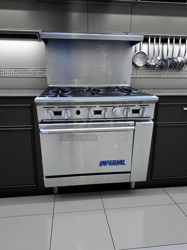 Imperial commercial range with multiple burners and oven. Stainless steel finish, six control knobs, large hood. Excellent condition.