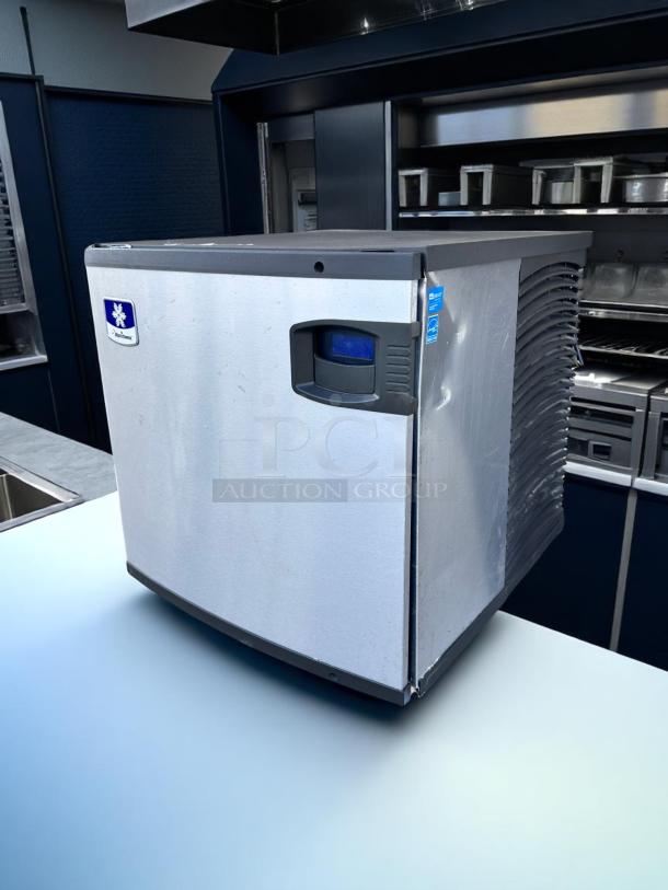 Commercial ice maker with stainless steel finish, front logo label indicating brand, compact design, minor surface wear, suitable for restaurant use.