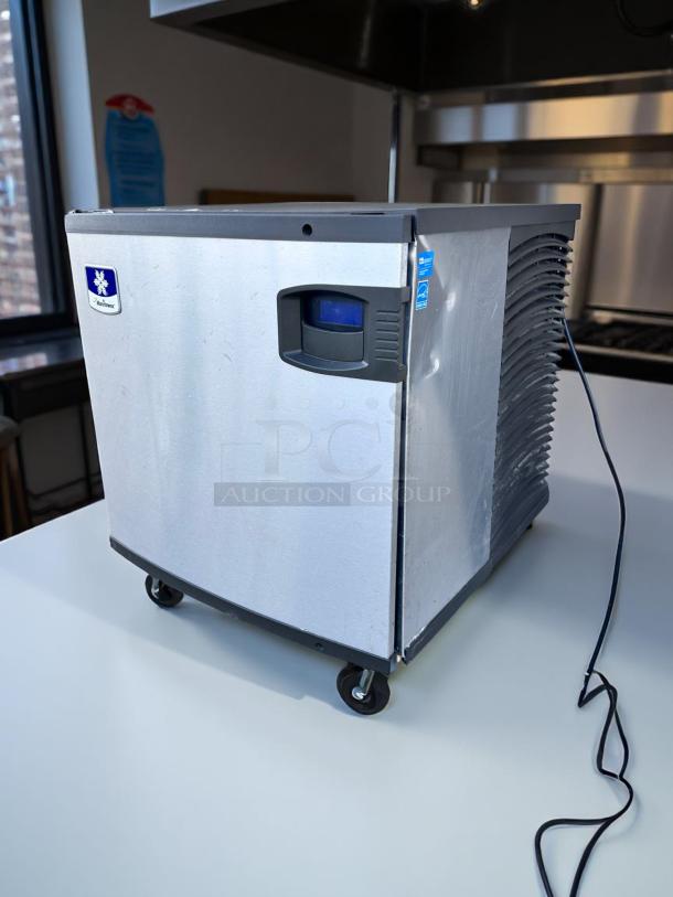 Manitowoc ice machine on wheels, stainless steel finish, minor scratches, model tag visible, in working condition.