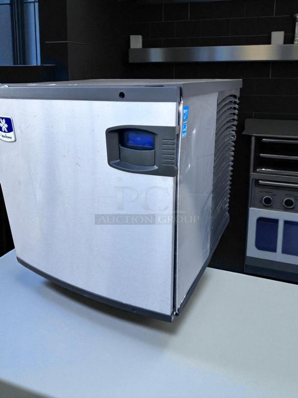 Stainless steel ice machine with visible Manitowoc logo, in good condition, near kitchen setup.