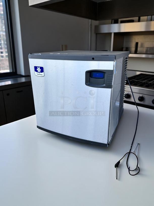 Manitowoc undercounter ice machine, stainless steel, minor surface wear, features a control panel.