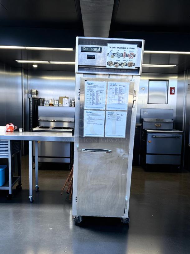 Stainless steel Continental food warming cabinet on wheels, visible labels with food allergen information, and some wear.