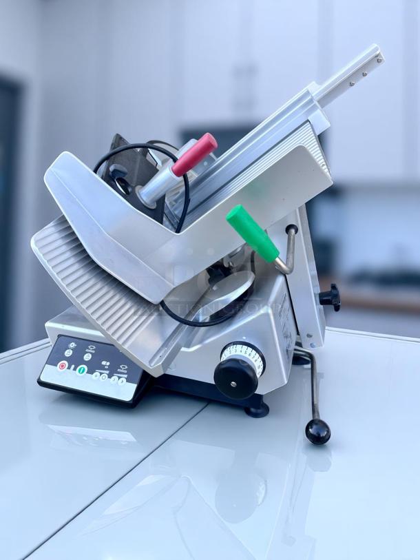 Commercial meat slicer with adjustable blade settings, metallic finish, and ergonomic handles. Appears in excellent condition.