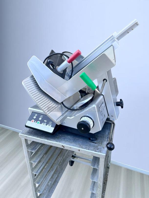 Commercial deli meat slicer on metal stand, features adjustable thickness dial, green and red handles, labeled control panel.
