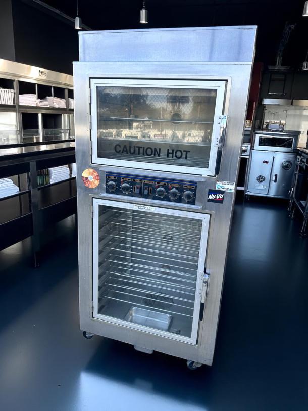 Nu-Vu double-deck commercial oven, stainless steel, "CAUTION HOT" label, control panel with dials, wheeled base.