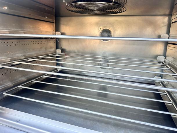 Commercial stainless steel convection oven interior with multiple racks, clean condition, large capacity, vented back panel.