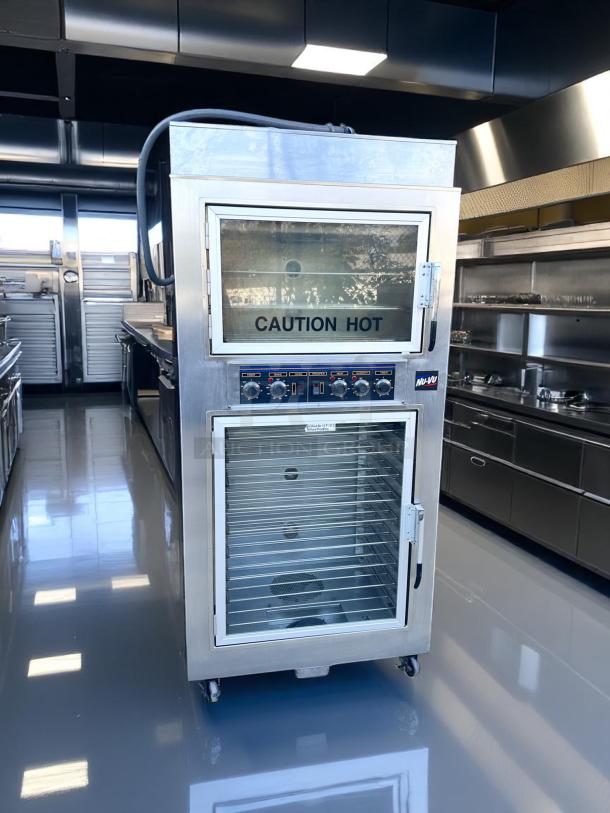Commercial stainless steel warming cabinet with glass doors, control knobs, "Caution Hot" label, on casters, excellent condition.