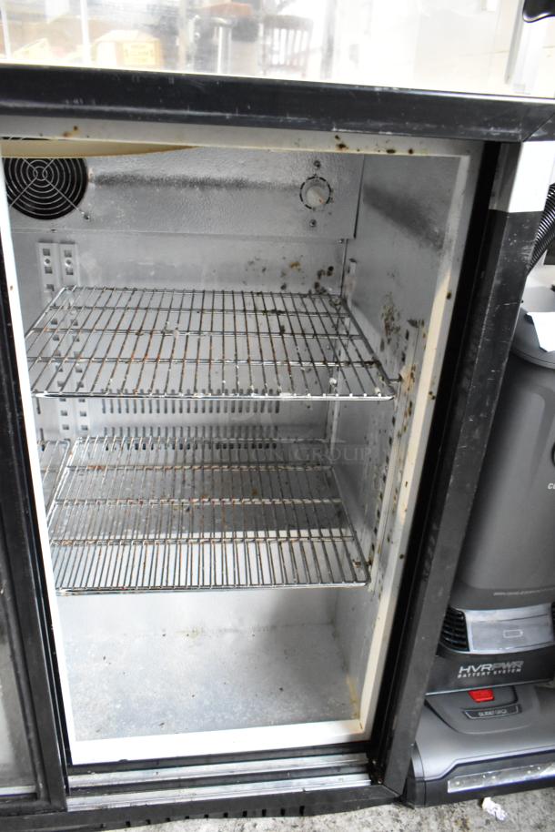 Open commercial refrigerator with two wire shelves, visible rust and dirt buildup inside, no tags or labels.