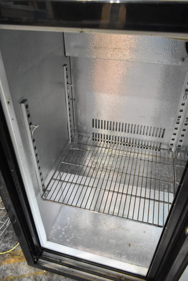 Commercial refrigerator interior with metal shelving, adjustable rack slots, and textured metallic finish showing signs of wear.