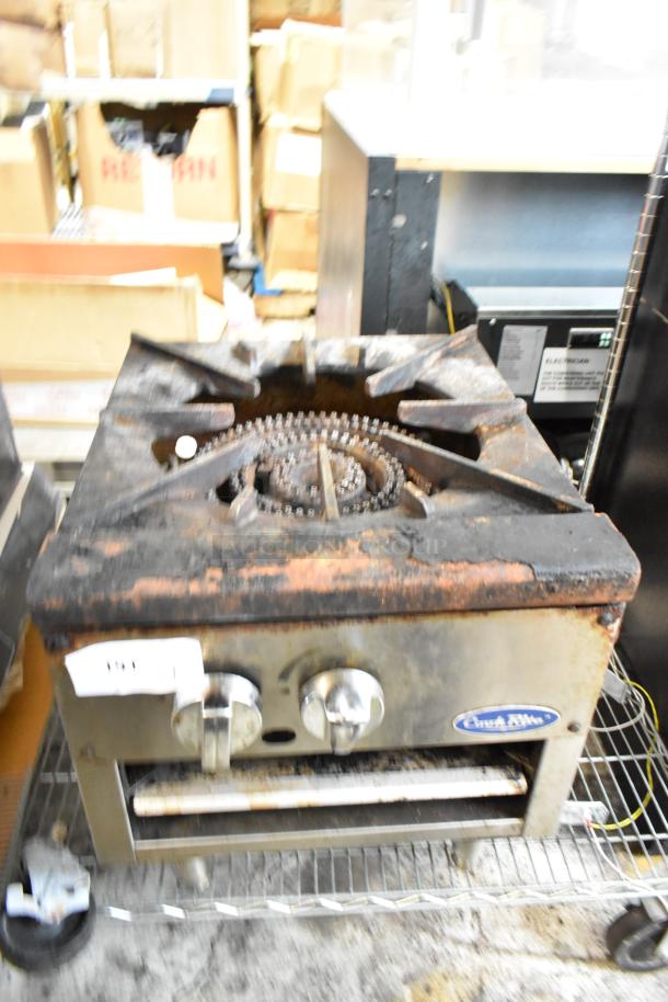Worn single-burner commercial stove, rusted, with two control knobs. Label reads "American Range." Auction tag visible.