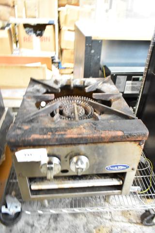 Worn single-burner commercial stove, rusted, with two control knobs. Label reads "American Range." Auction tag visible.