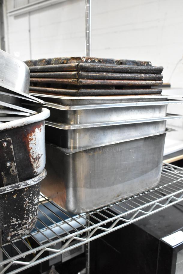 Stack of used metal baking trays and pans on a wire shelf, showing signs of rust and wear. Ideal for commercial kitchen use.