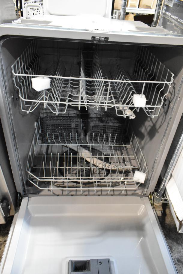Open dishwasher with stainless steel interior, dual racks, and secure packaging inserts. Appears new, no visible damage.