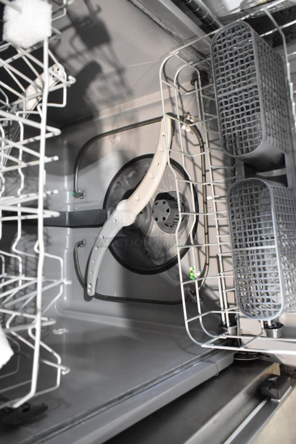 Interior of a dishwasher with silver metal racks, gray utensils basket, and spray arm. Appears clean and in good condition.