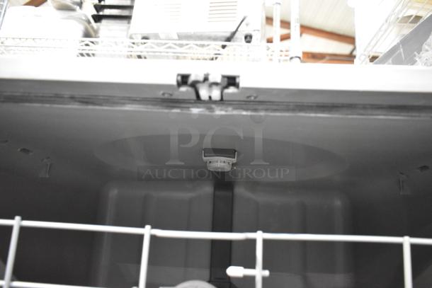 Industrial dishwasher interior, gray, visible spray arm and racks, clean condition, suitable for commercial kitchens.