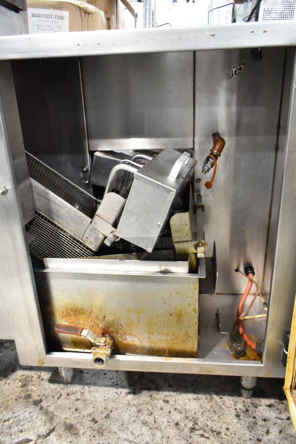 Commercial deep fryer, stainless steel, used condition with visible grease stains and rust on drain valve, interior components exposed.