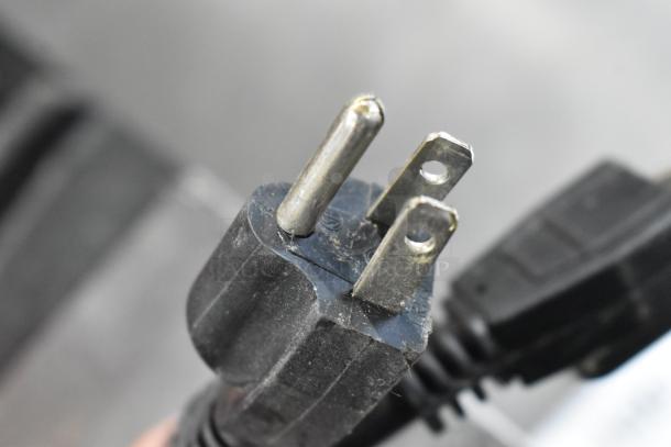 Close-up of a used two-prong power plug with visible wear, black casing, and slight discoloration on metal prongs.